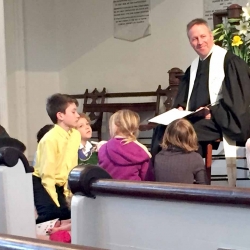 Rev. Brent Damrow smiles at the children surrounding him during his children's message