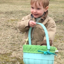 A young boy smiles with delight as he inspects his Easter egg basket