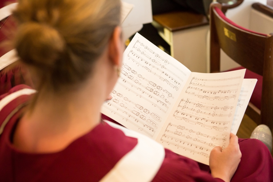 Close up shot of a woman in choir rehearsal with sheet music in her hands