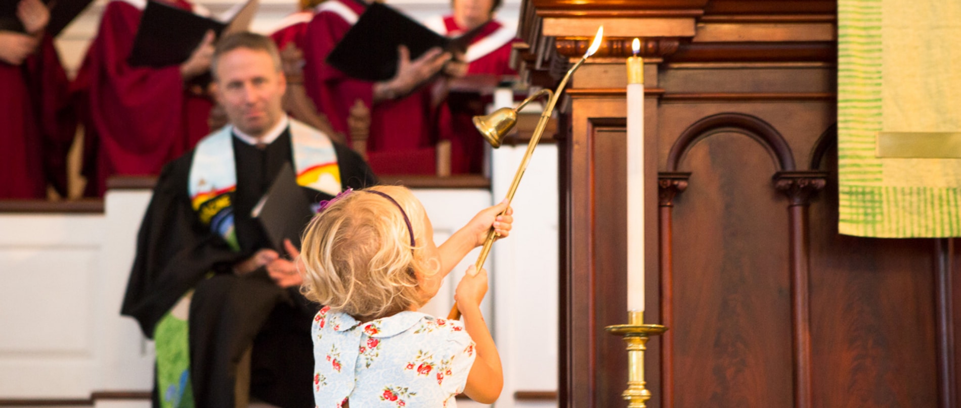 A young girl lights a candle to begin worship