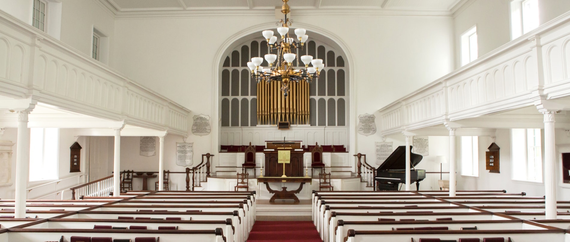 The historic sanctuary of the Stockbridge Congregational Church with white interior and red upholstry.