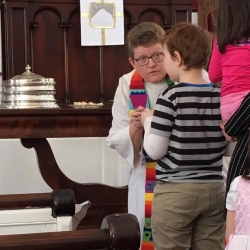 Rev. Patty Fox serves communion to a young boy