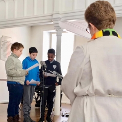 Three tenage boys participating in worship bid farewell to Rev. Patty Fox