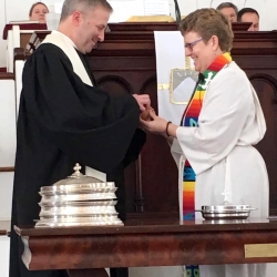 Rev. Brent Damrow and Rev. Patty Fox serve each other communion