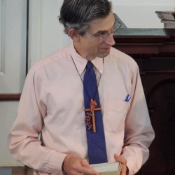 A Sunday School teacher receives a cross from the congregation in thanks for his service