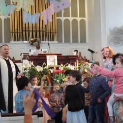 Children wave decorative butterflies while singing Alleluia