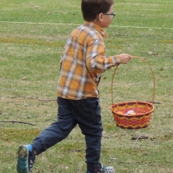 A boy runs across the lawn in search of Easter eggs