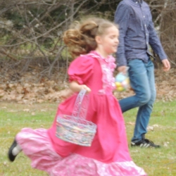 A girl in a pink dress hunts for easter eggs