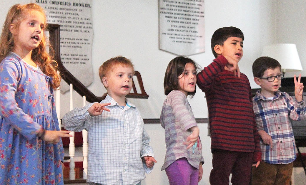Three boys and two girls sing in church