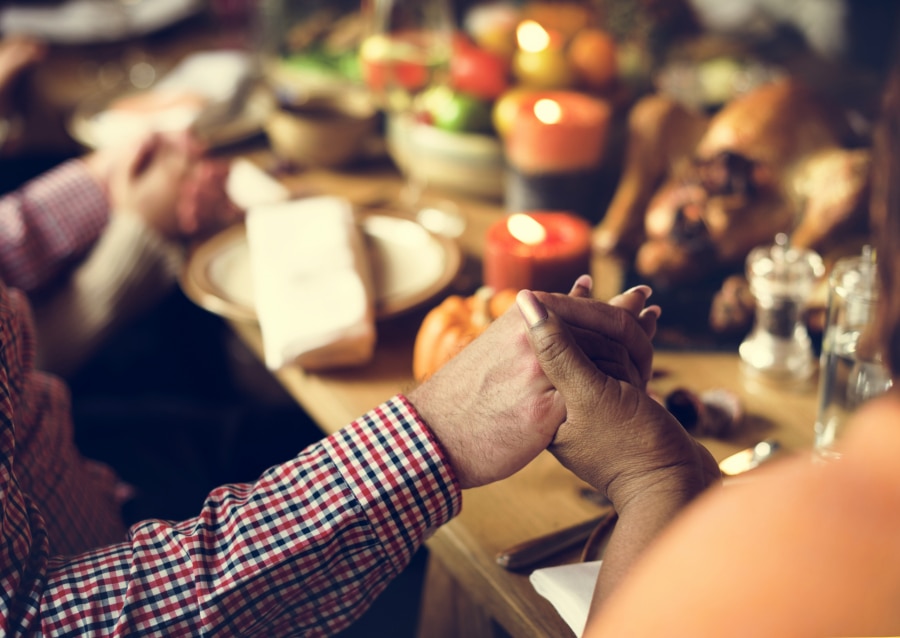 People hold hands and pray at the Thanksgiving Dinner Table