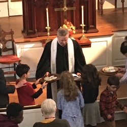 The pastor receives the offering from a group of children