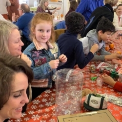 Children and parents work on Christmas ornaments