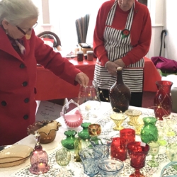 A woman looks at antique glassware for sale