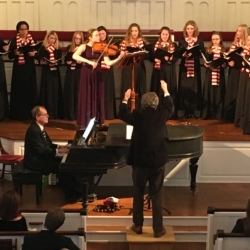 A young women's choir is accompanied by a violist