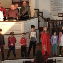 A group of children sing in a church