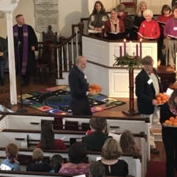 People pass out oranges as part of the Christingle service