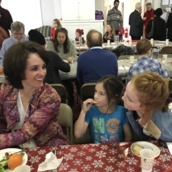 A woman and two children eating lunch at the Advent potluck