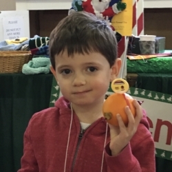 A boy shows off his completed Christingle