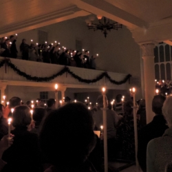 The sanctuary lit by candles held by congregants as they sing Silent Night.