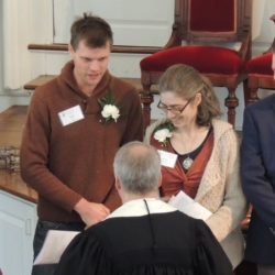 The pastor shakes the hands of a young married couple to welcome them into the church