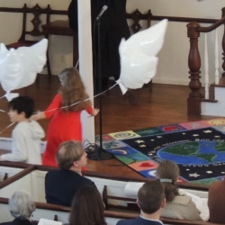Children walk around the sanctuary holding dove-shaped balloons.