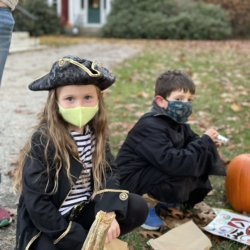 A girl dressed as a pirate decorates a pumpkin